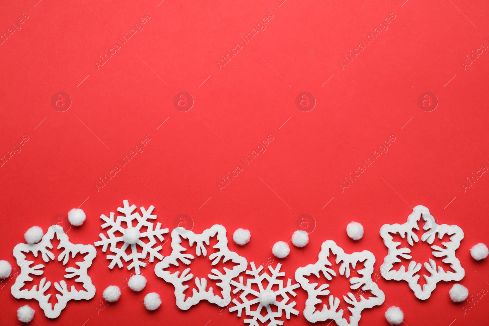 Photo of Beautiful decorative snowflakes on red background, flat lay. Space for text