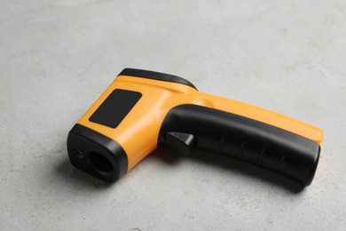 Photo of Modern non-contact infrared thermometer on light grey stone background