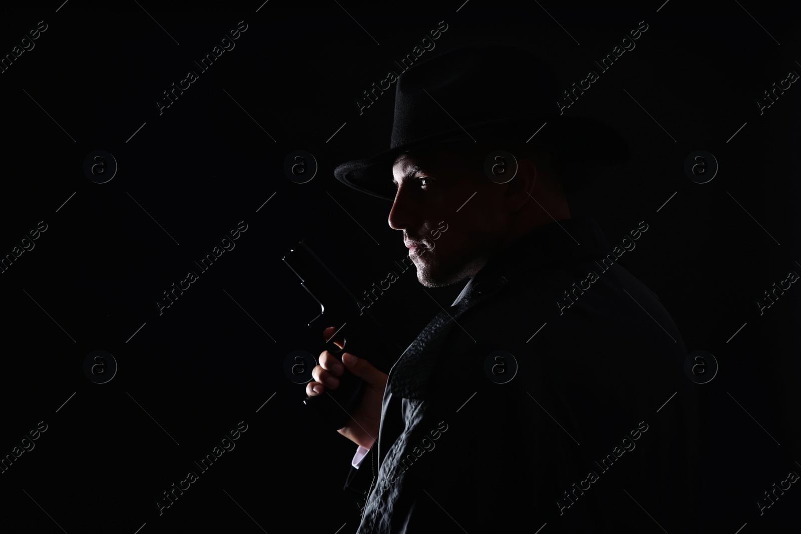 Photo of Old fashioned detective with gun on dark background. Space for text