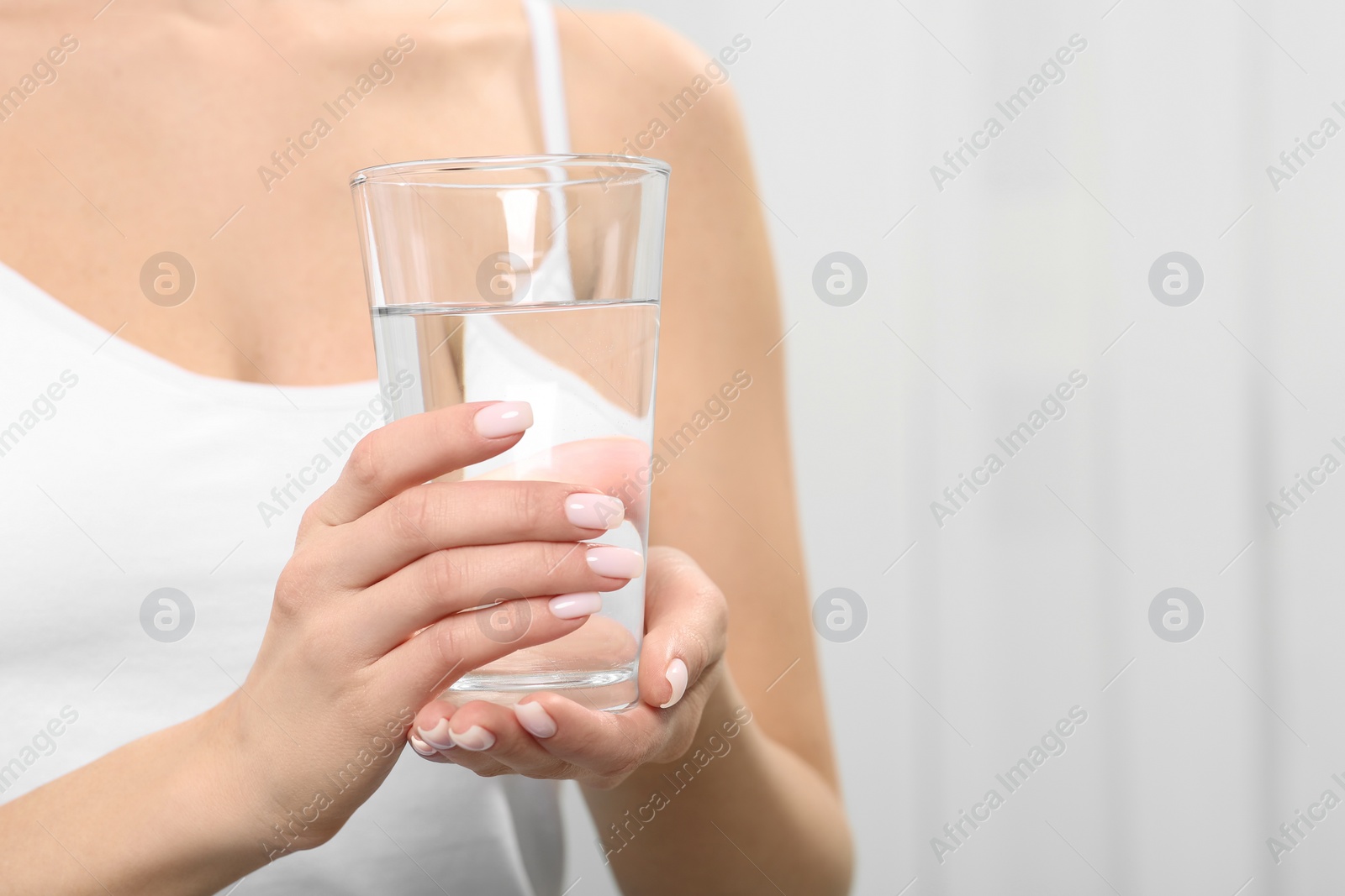 Photo of Healthy habit. Closeup of woman holding glass with fresh water indoors, space for text