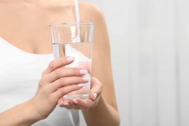 Photo of Healthy habit. Closeup of woman holding glass with fresh water indoors, space for text