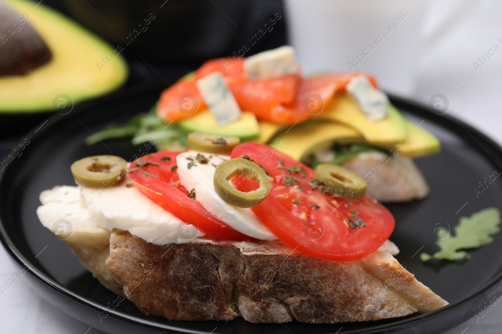 Photo of Different tasty bruschettas on black plate, closeup