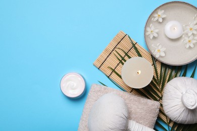 Flat lay composition with spa products, burning candle and beautiful flowers on light blue background. Space for text