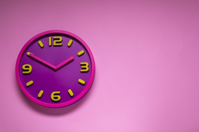 Photo of Stylish round clock on pale pink background, top view with space for text. Interior element