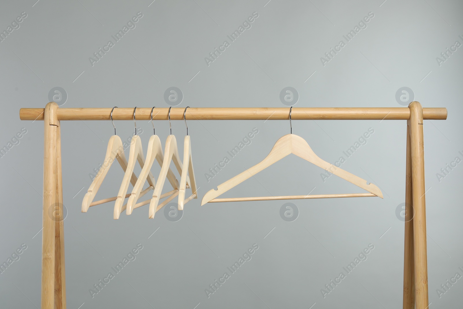 Photo of Empty clothes hangers on wooden rack against grey background