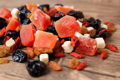 Photo of Pile of different tasty dried fruits on wooden table, closeup