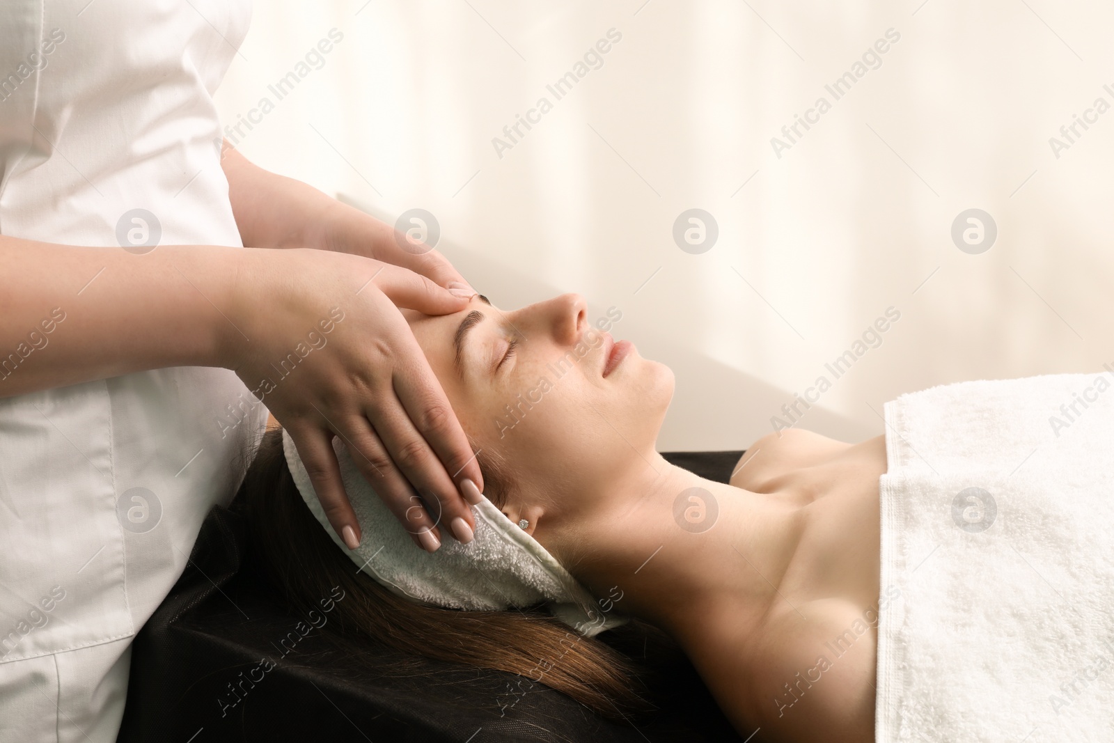 Photo of Cosmetologist making face massage to client in clinic, closeup