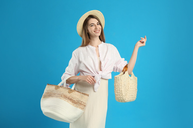 Photo of Beautiful young woman with stylish bags on light blue background