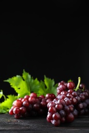 Fresh ripe juicy grapes on grey table against black background, space for text