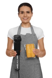 Photo of Beautiful young woman holding sous vide cooker and corn in vacuum pack on white background