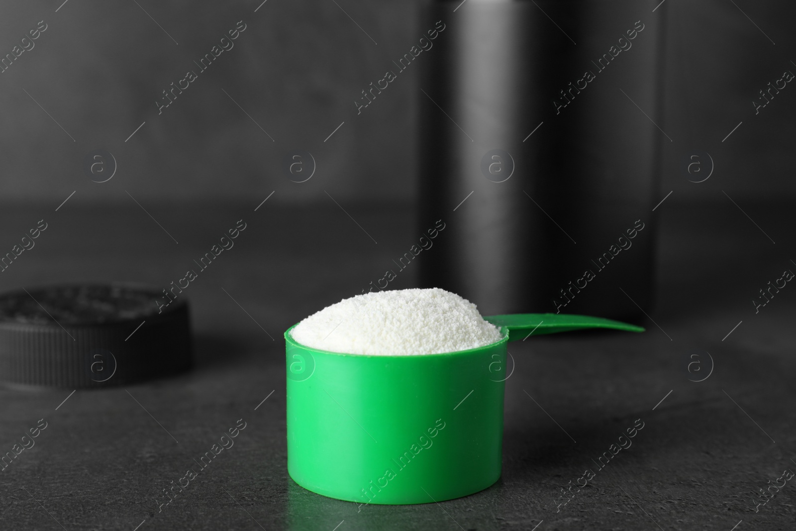 Photo of Scoop of protein powder on grey stone table