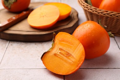 Photo of Delicious ripe juicy persimmons on tiled surface