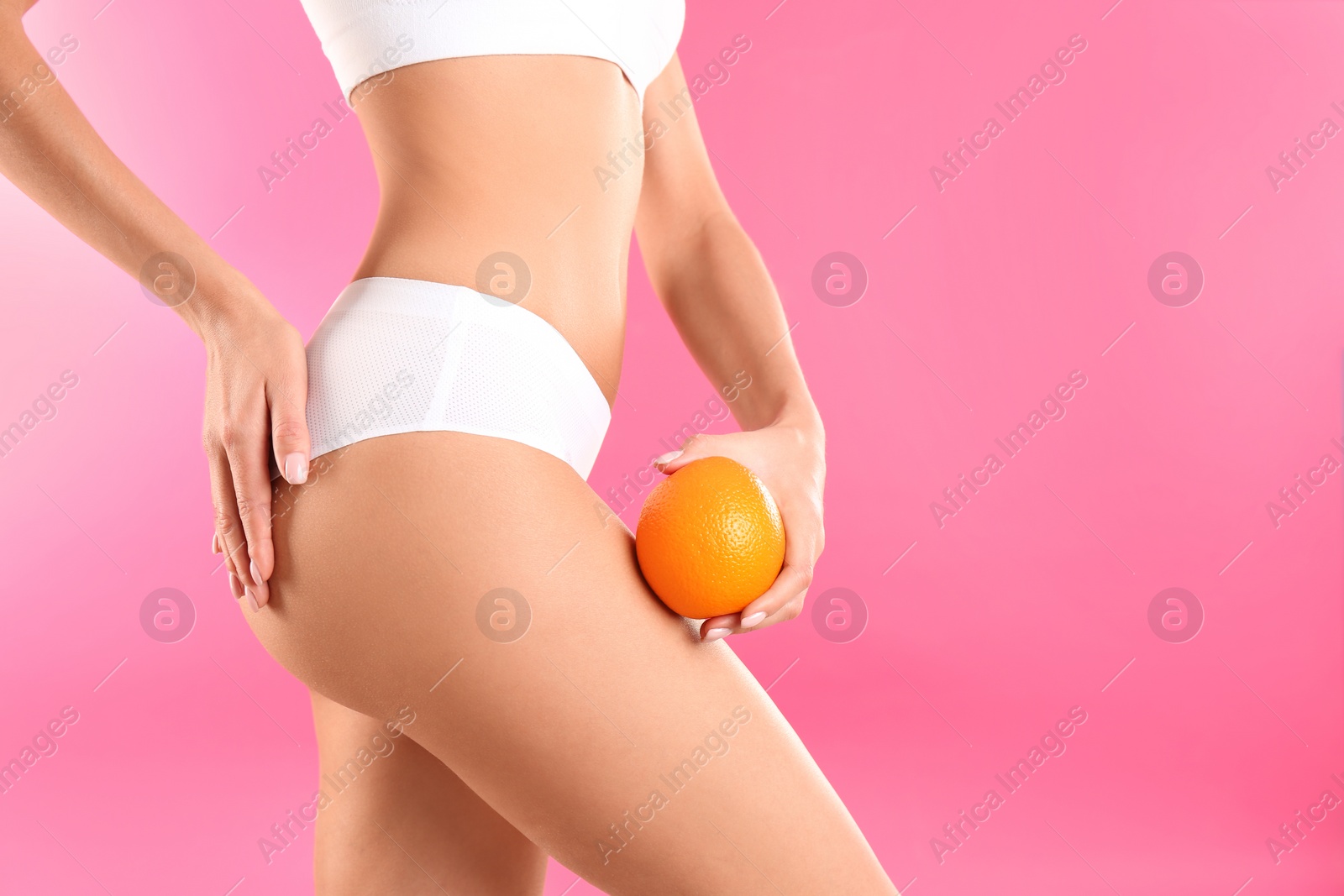 Photo of Closeup view of slim woman in underwear with orange on color background, space for text. Cellulite problem concept