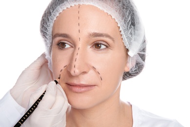 Doctor marking mature woman face before cosmetic surgery on white background