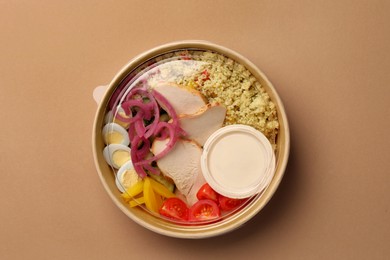 Photo of Tasty food in container on beige background, top view