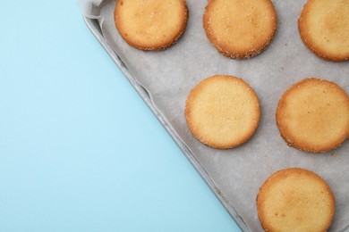 Photo of Tray with tasty sweet sugar cookies on light blue background, top view. Space for text