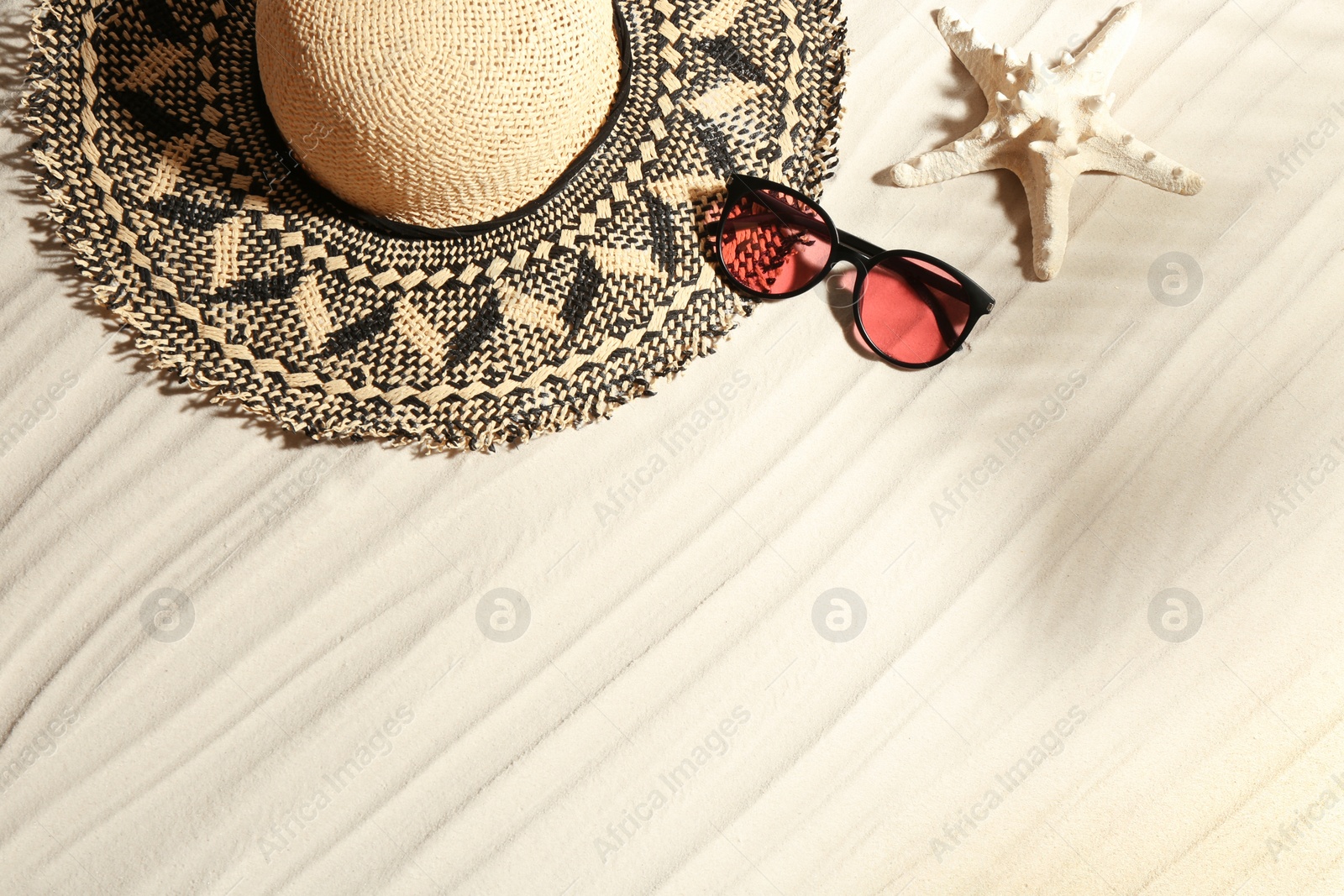 Photo of Stylish hat, sunglasses and starfish on sand, flat lay with space for text. Beach accessories