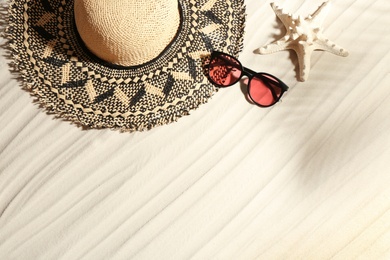 Stylish hat, sunglasses and starfish on sand, flat lay with space for text. Beach accessories