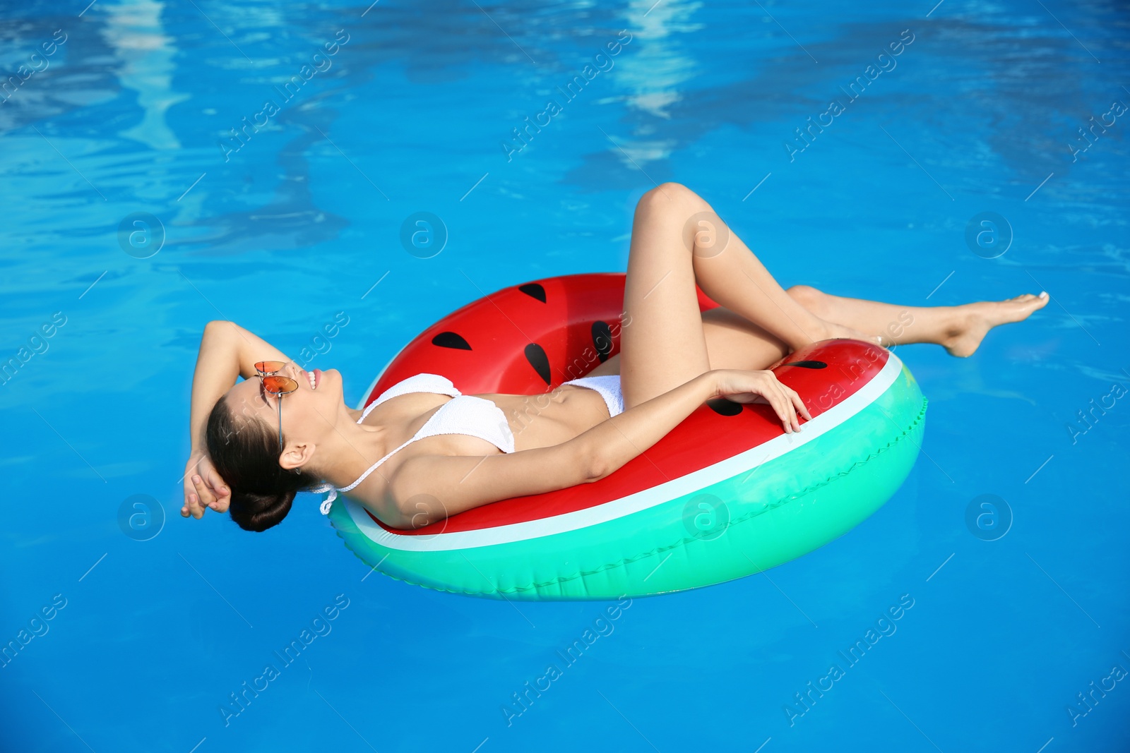 Photo of Beautiful young woman wearing bikini on inflatable ring in swimming pool