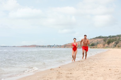 Photo of Professional lifeguards running at sandy beach on sunny day
