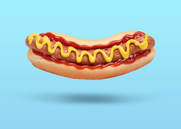 Yummy hot dog with ketchup and mustard in air against light blue background