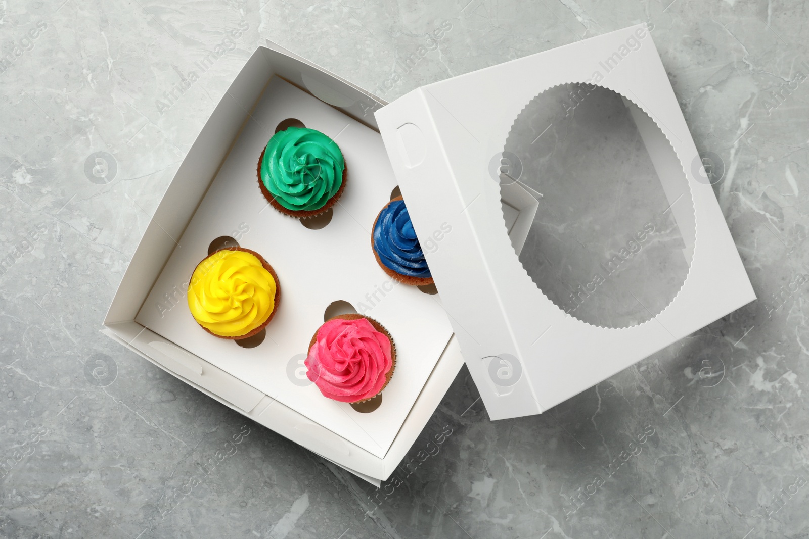 Photo of Box with different cupcakes on grey table, top view