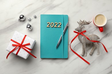 Turquoise planner, cup of coffee and Christmas decor on white marble background, flat lay. 2022 New Year aims