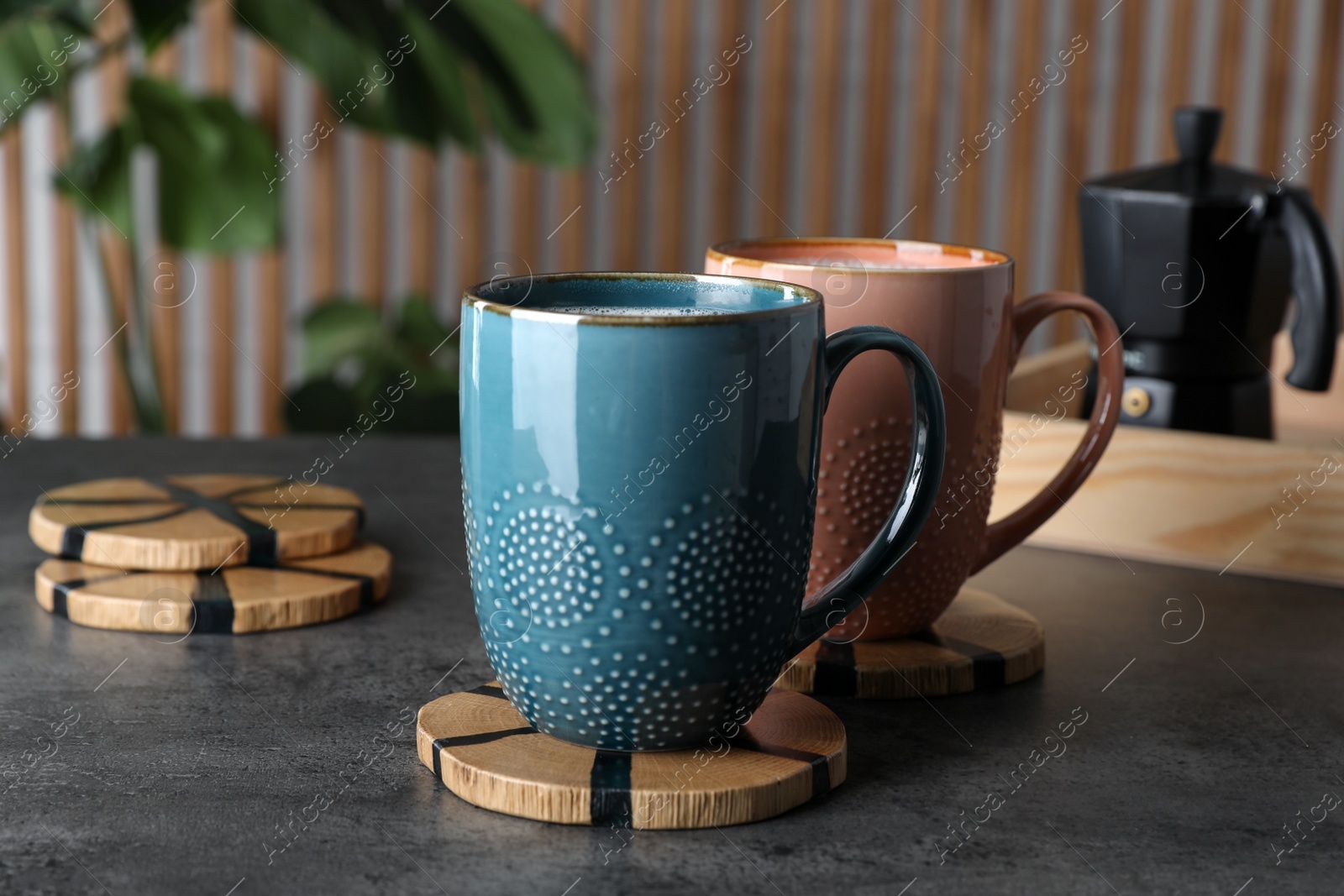 Photo of Mugs of hot drink with stylish cup coasters on grey table