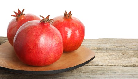 Photo of Fresh pomegranates on wooden table against white background, space for text