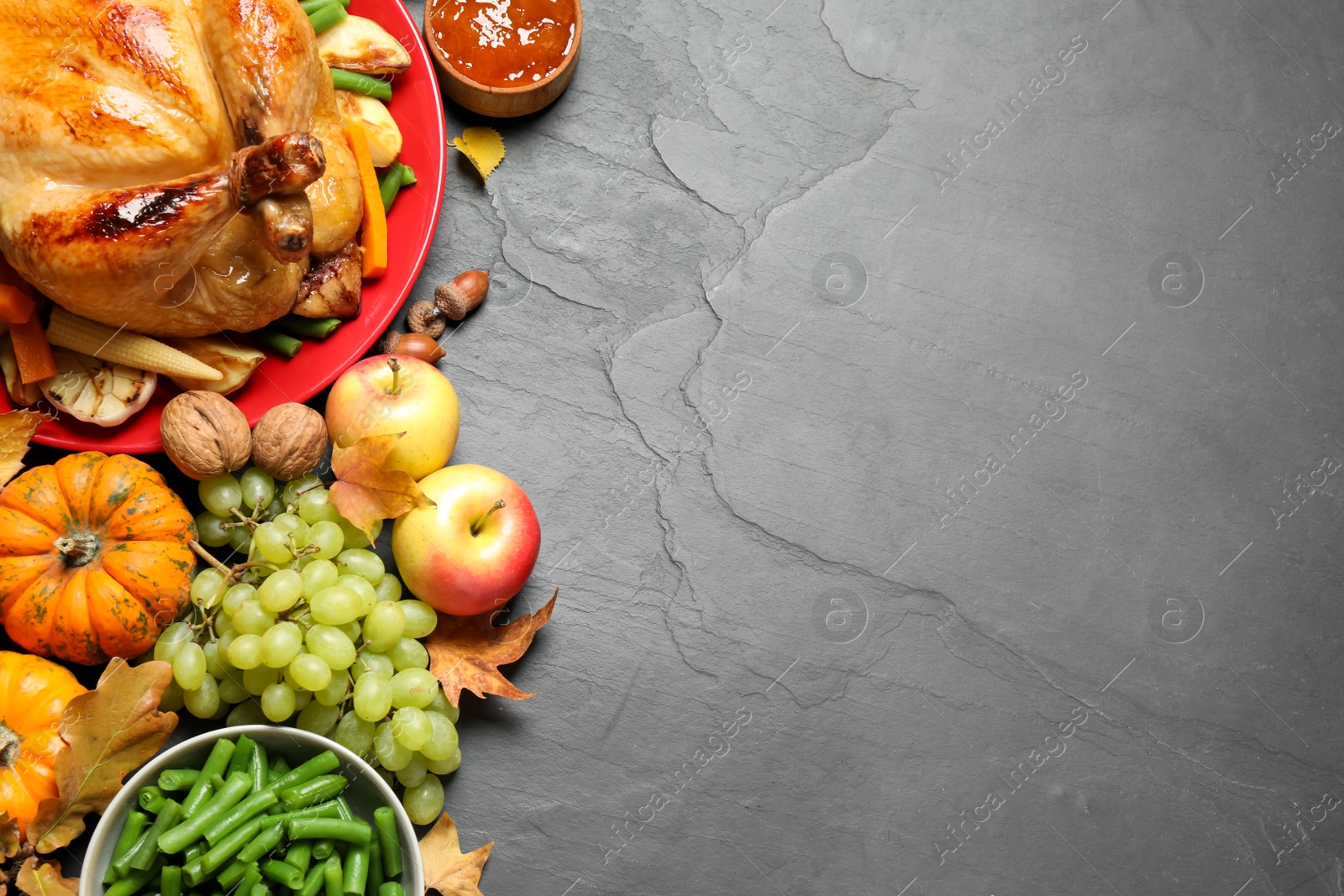 Photo of Traditional Thanksgiving day feast with delicious cooked turkey and other seasonal dishes served on black table, flat lay. Space for text