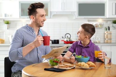 Photo of Dad and son having breakfast together in kitchen