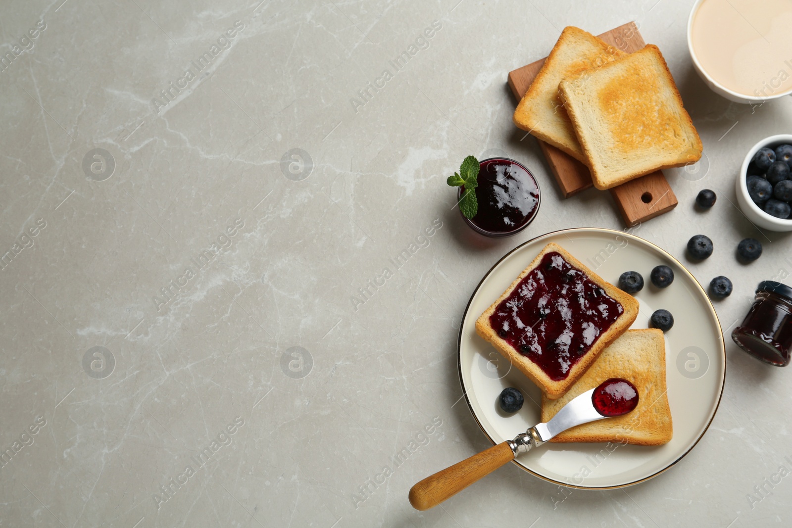 Photo of Toasts, blueberry jam and cup of coffee served on light marble table, flat lay. Space for text