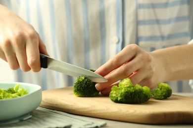 Photo of Woman cutting boiled broccoli at table, closeup. Child's food