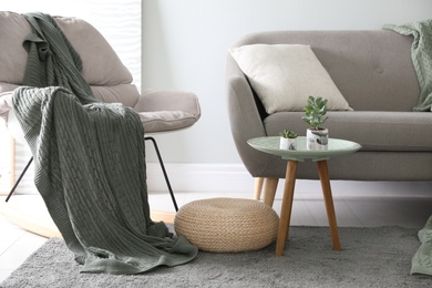 Photo of Soft knitted blanket on armchair in room. Home interior
