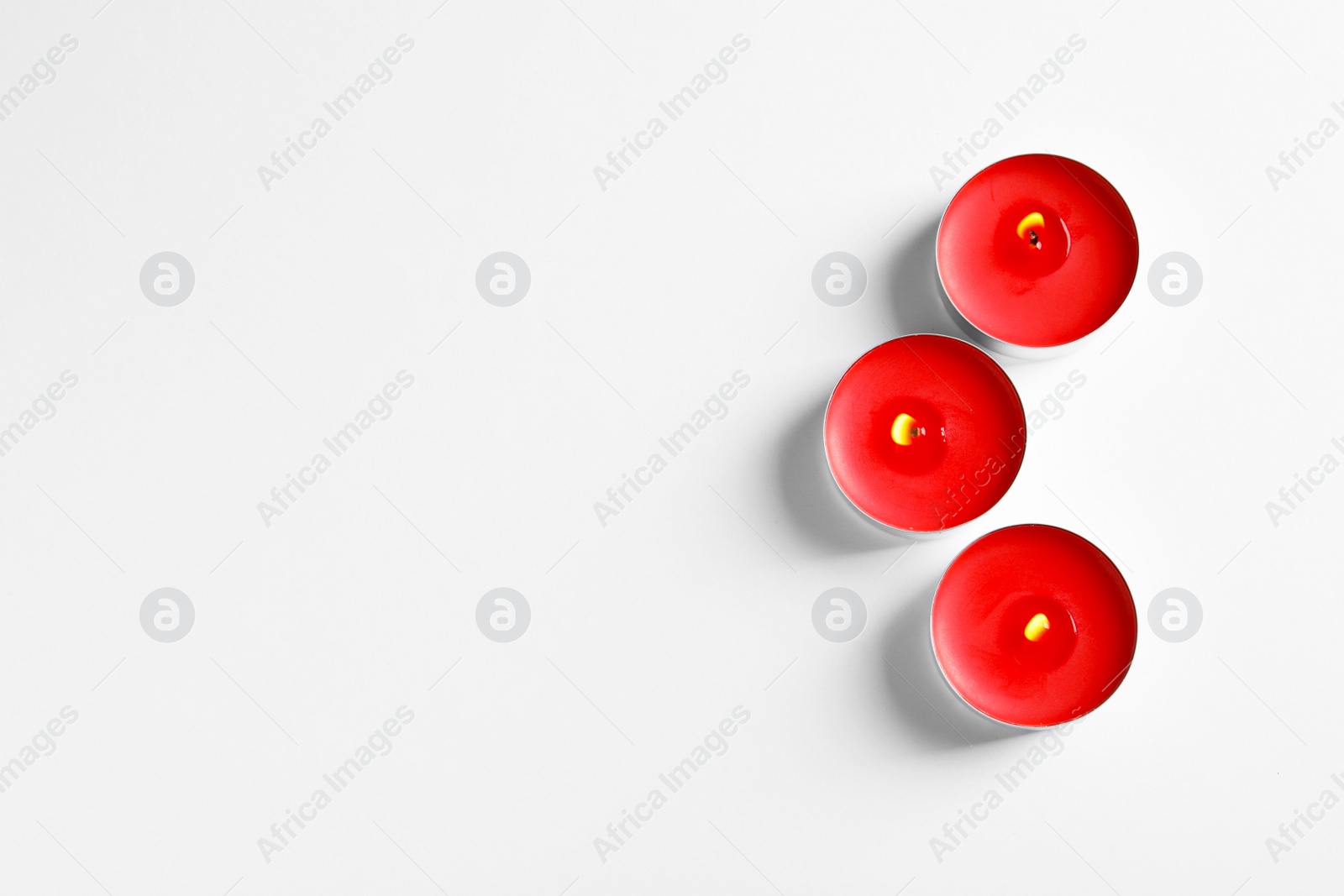 Photo of Burning wax candles on white background, top view