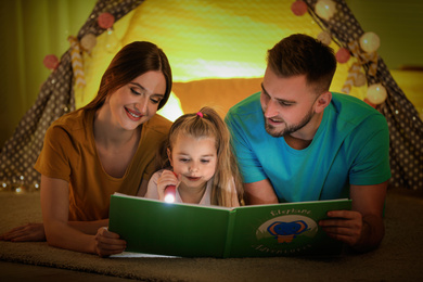 Photo of Family with flashlight reading book at home