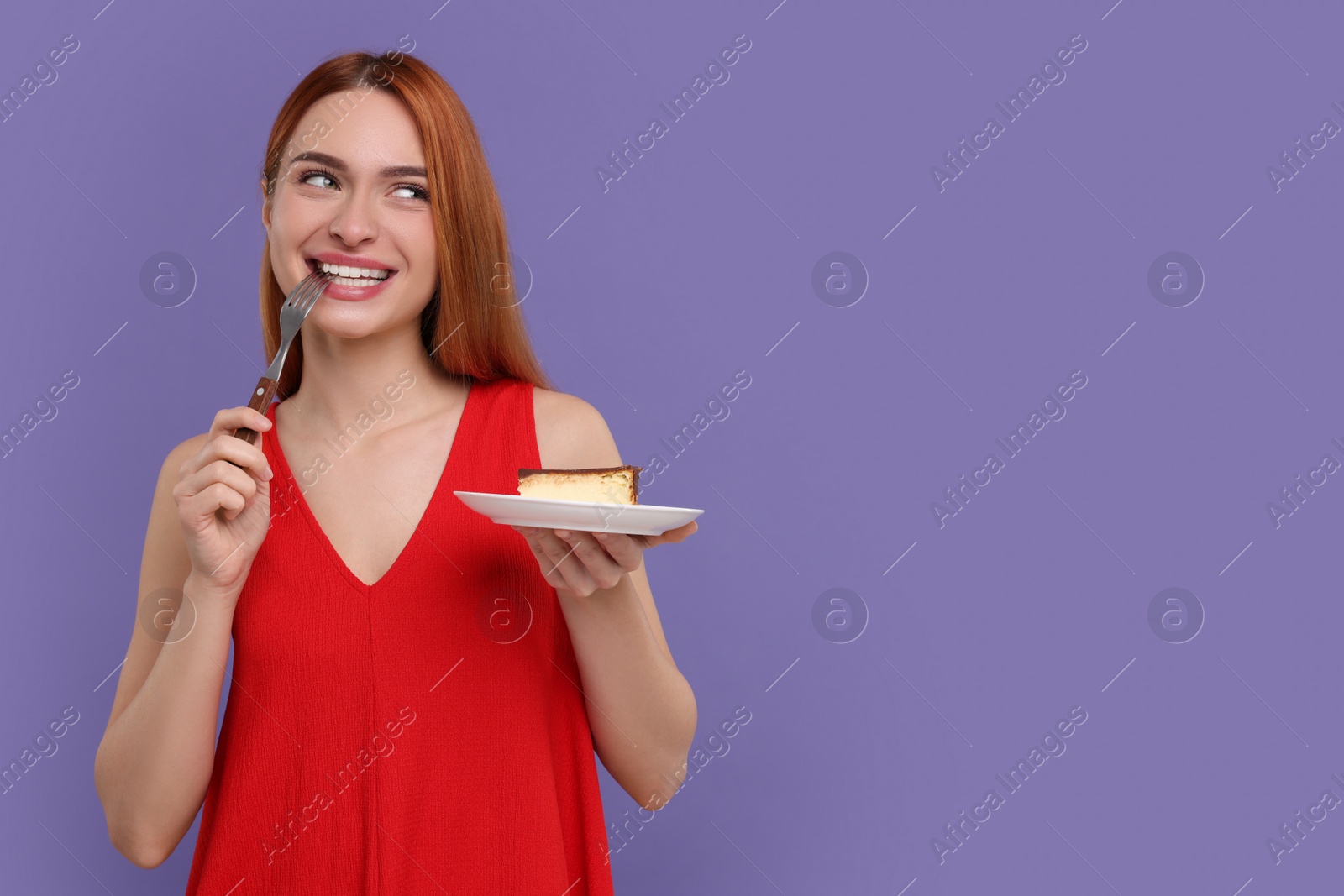 Photo of Young woman eating piece of tasty cake on purple background, space for text