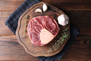 Photo of Piece of raw beef meat, thyme and garlic on wooden table, top view