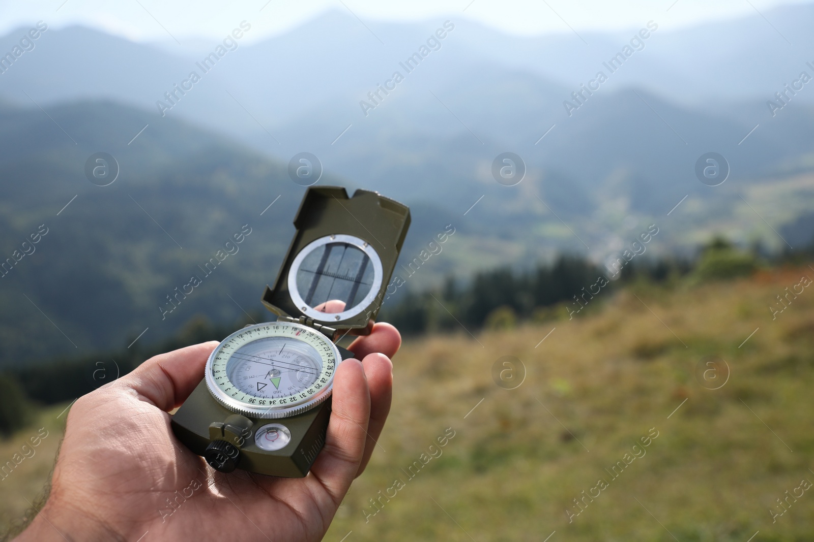 Photo of Man using compass during journey in mountains, closeup