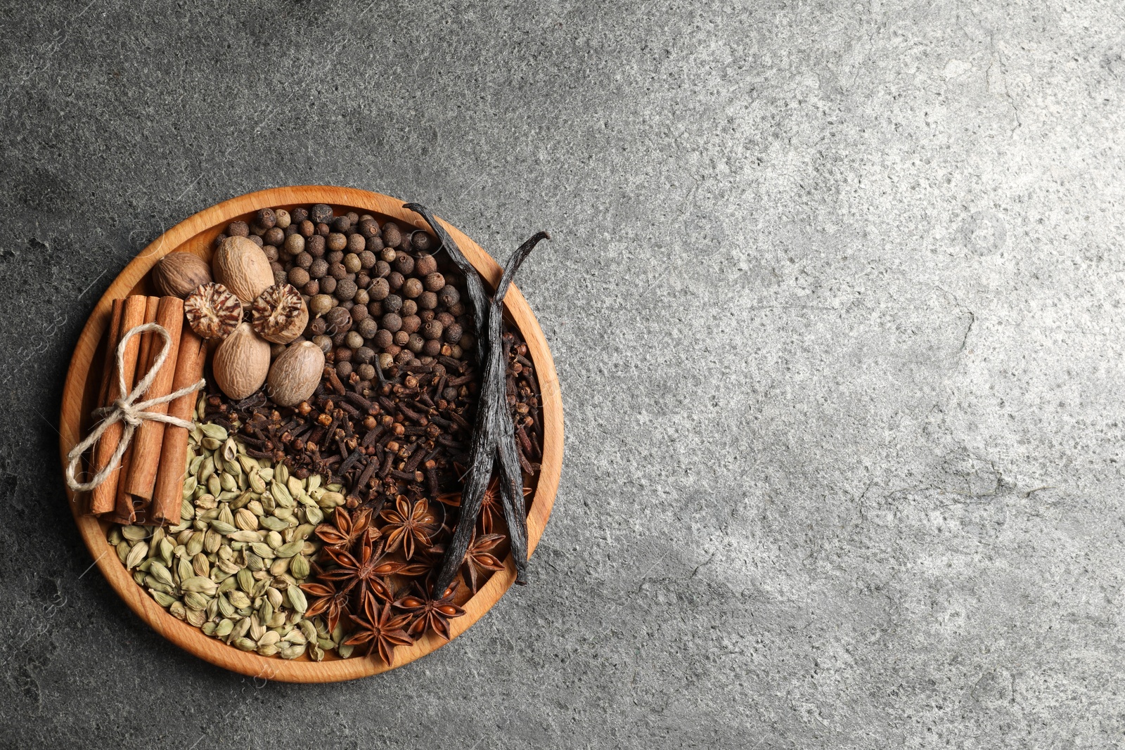 Photo of Different spices and nuts on gray textured table, top view. Space for text