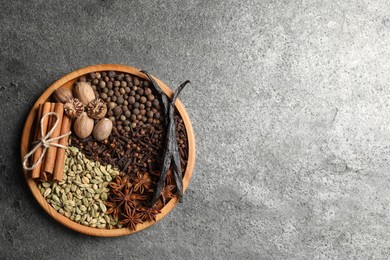 Photo of Different spices and nuts on gray textured table, top view. Space for text