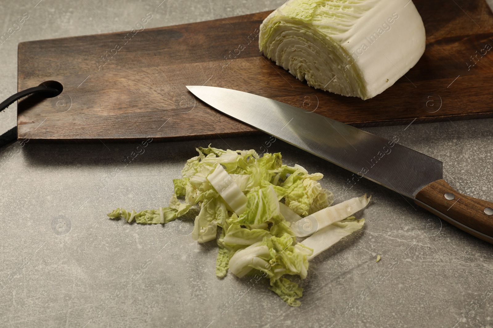 Photo of Cut fresh Chinese cabbage and knife on light grey table