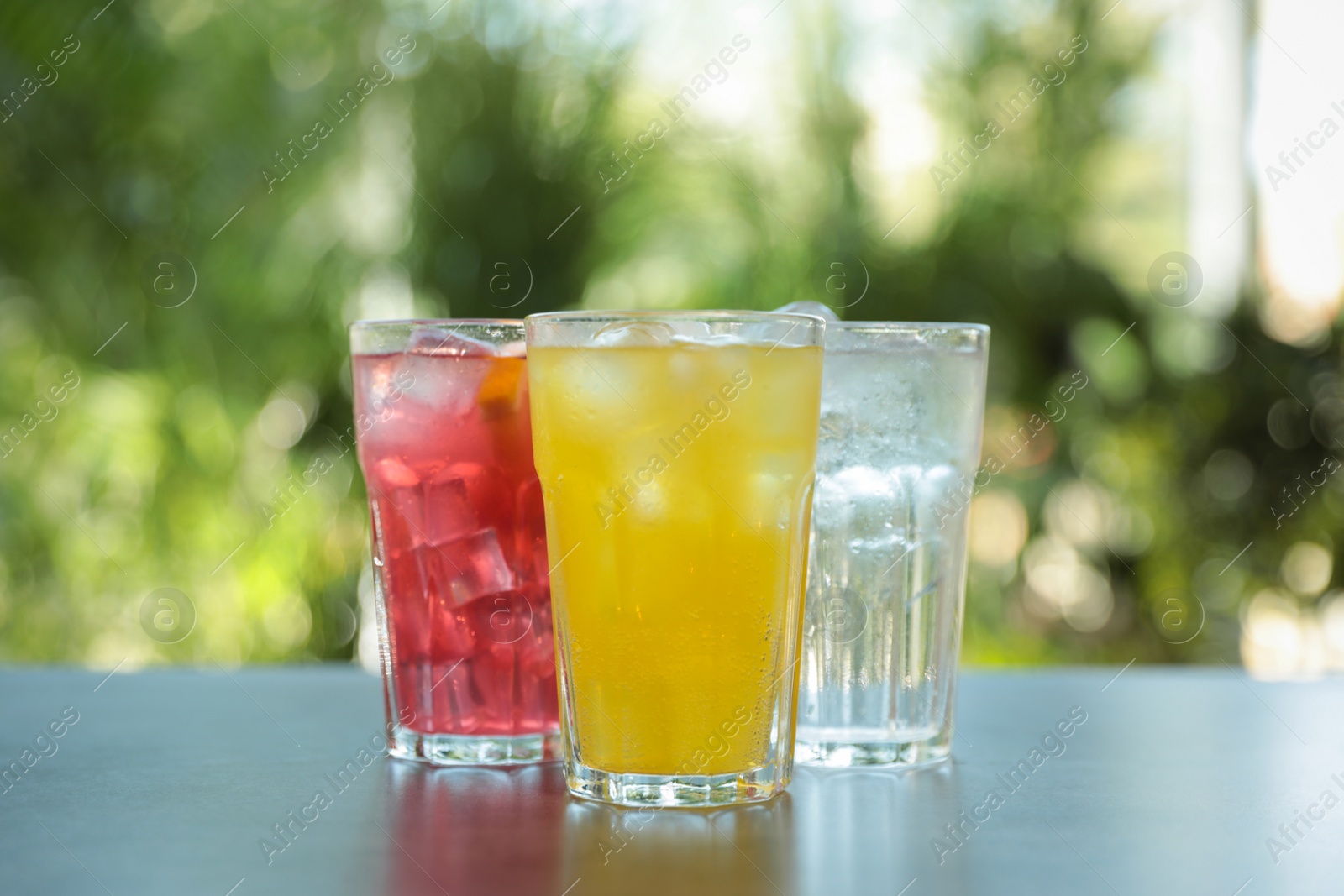 Photo of Delicious refreshing drinks in glasses on grey table outdoors