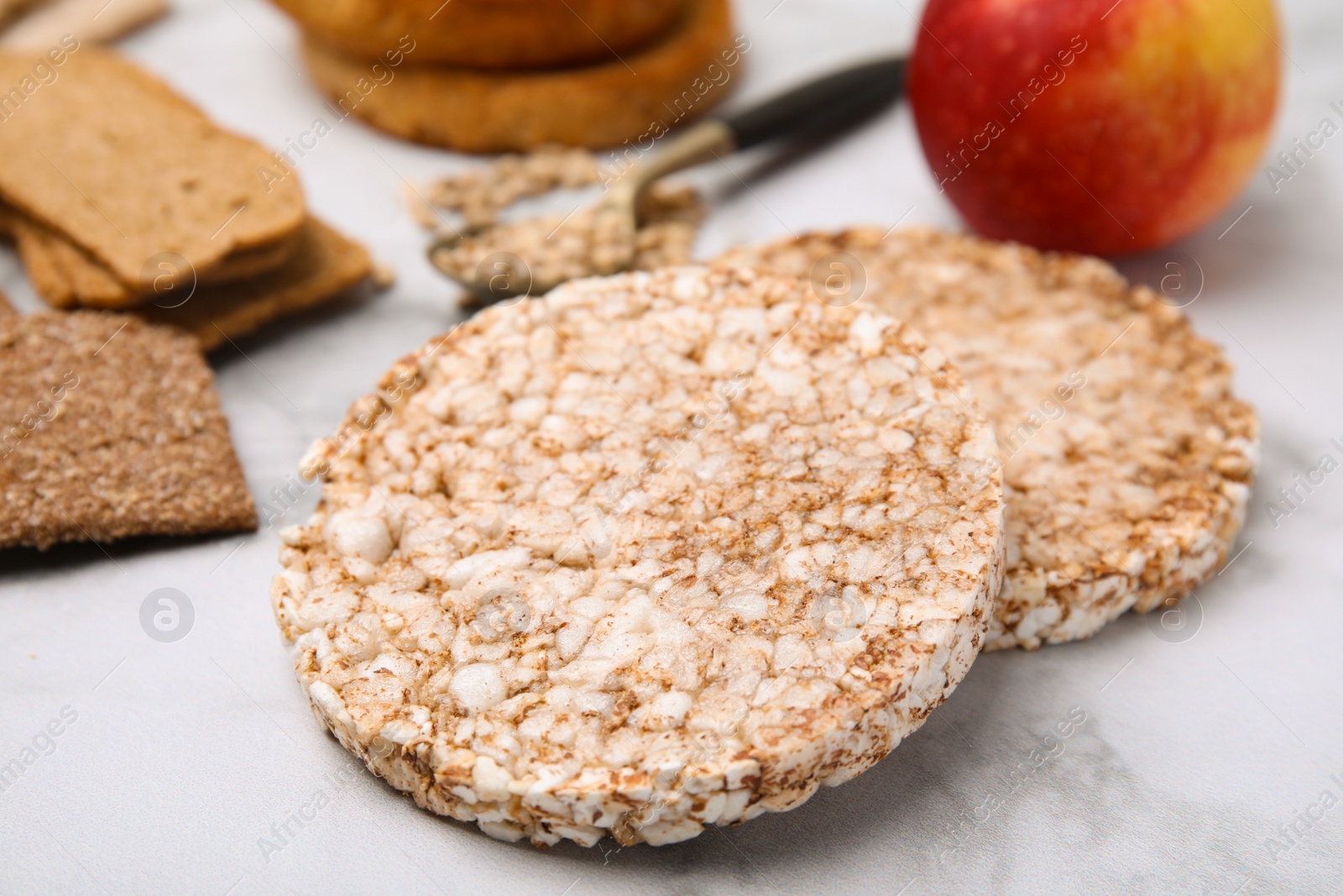 Photo of Rice cakes and rusks on white marble table, closeup