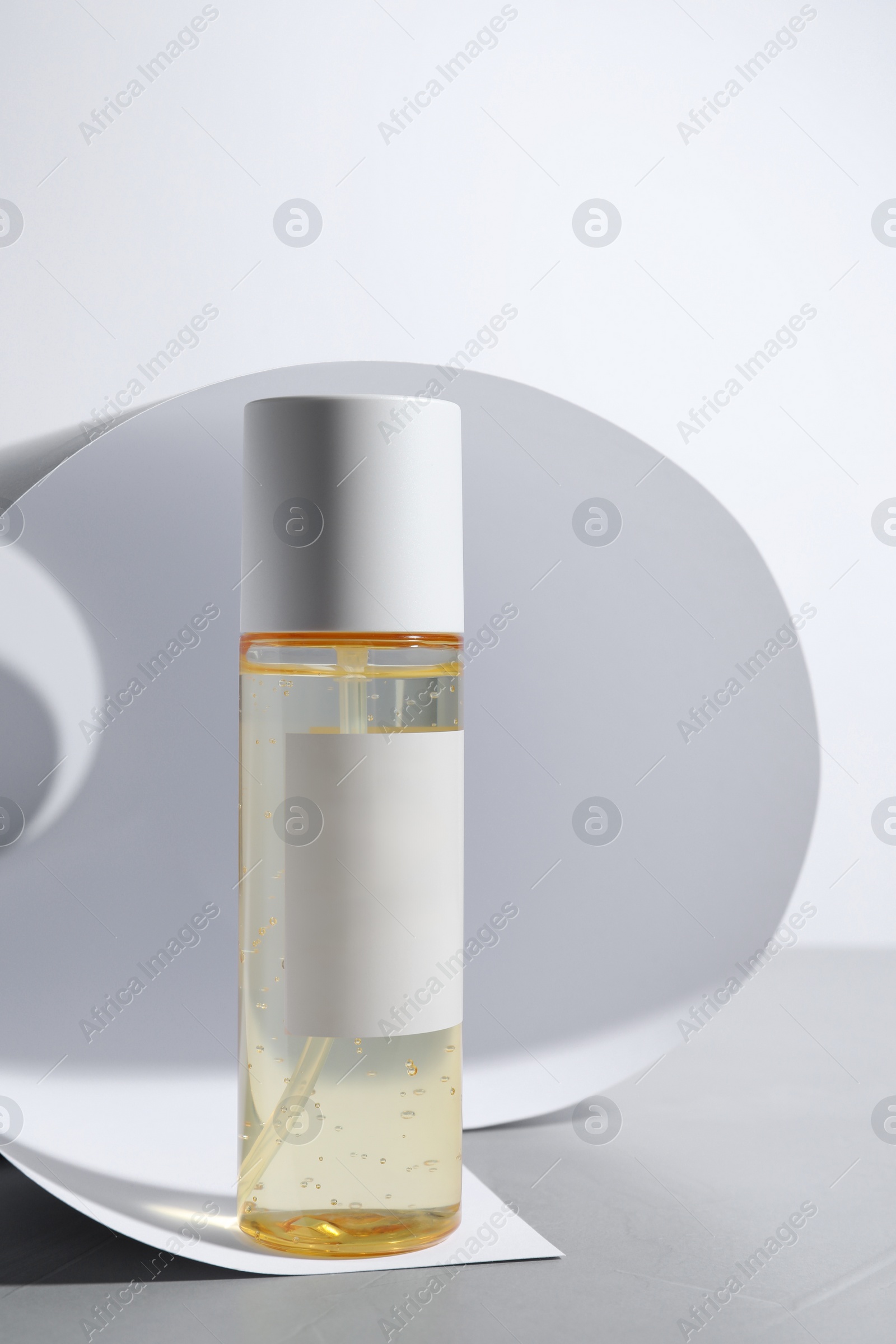 Photo of Bottle of cosmetic product on light grey table