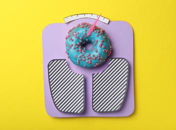 Photo of Scales made with donut on yellow background, top view