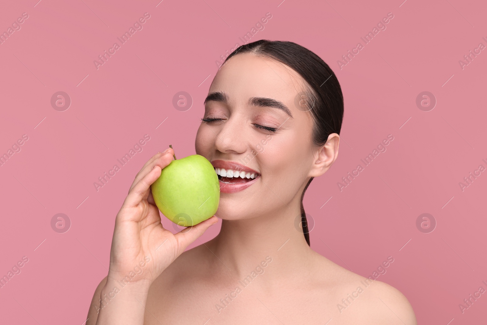 Photo of Beautiful young woman with apple on pink background
