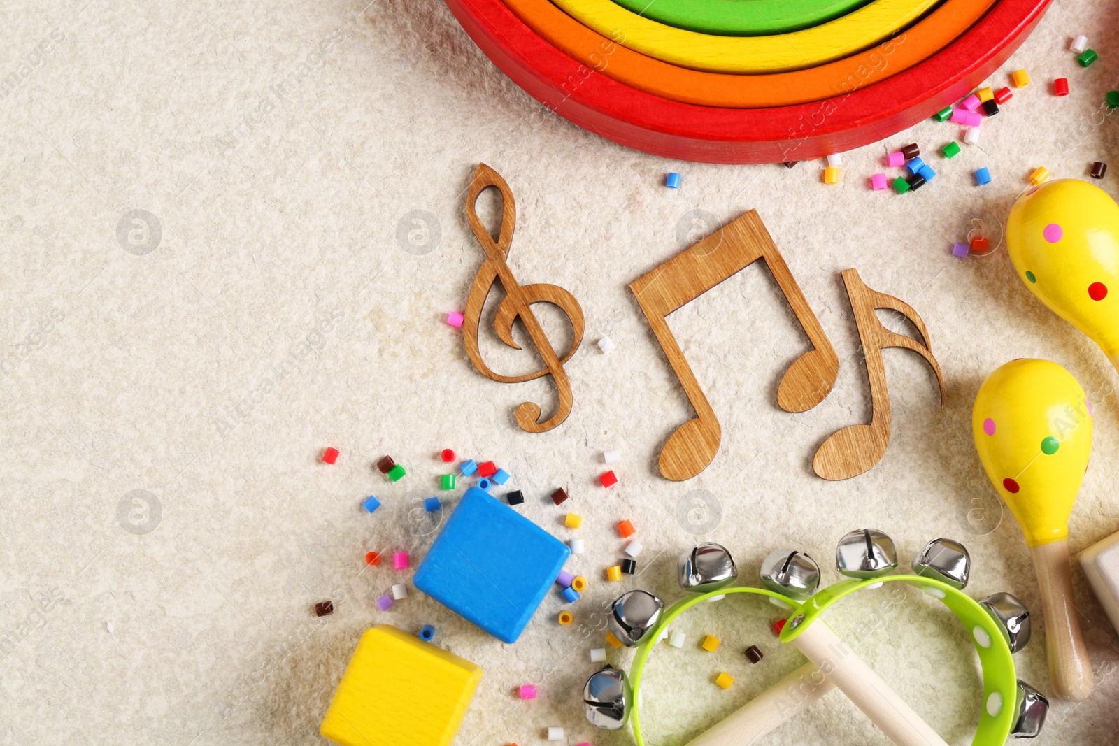 Photo of Baby song concept. Wooden notes, kids musical instruments and toys on beige carpet, flat lay. Space for text