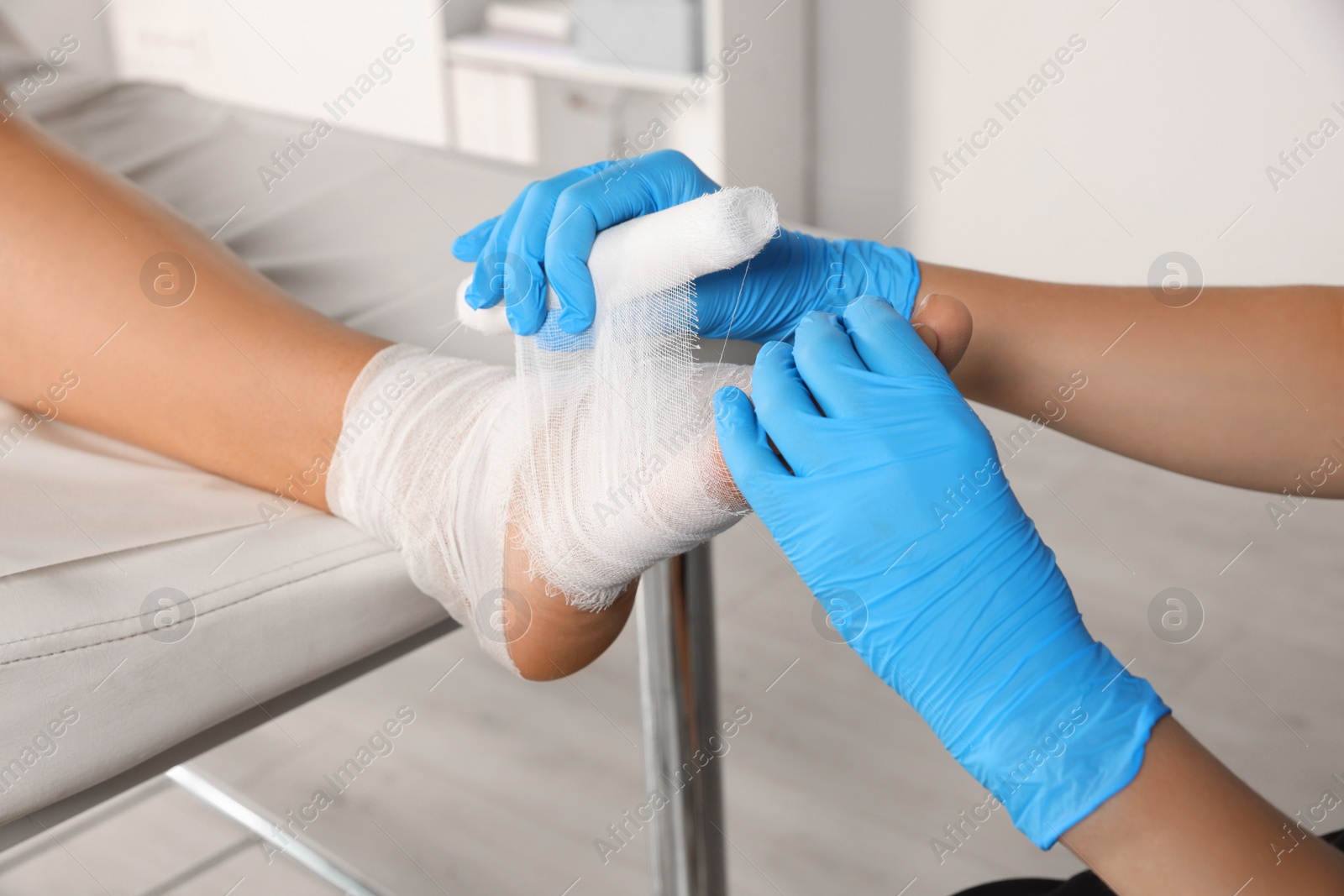 Photo of Doctor applying bandage onto patient's foot in hospital, closeup