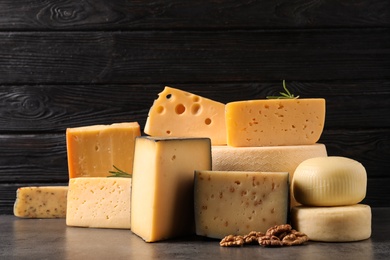 Different types of delicious cheese on table against wooden background